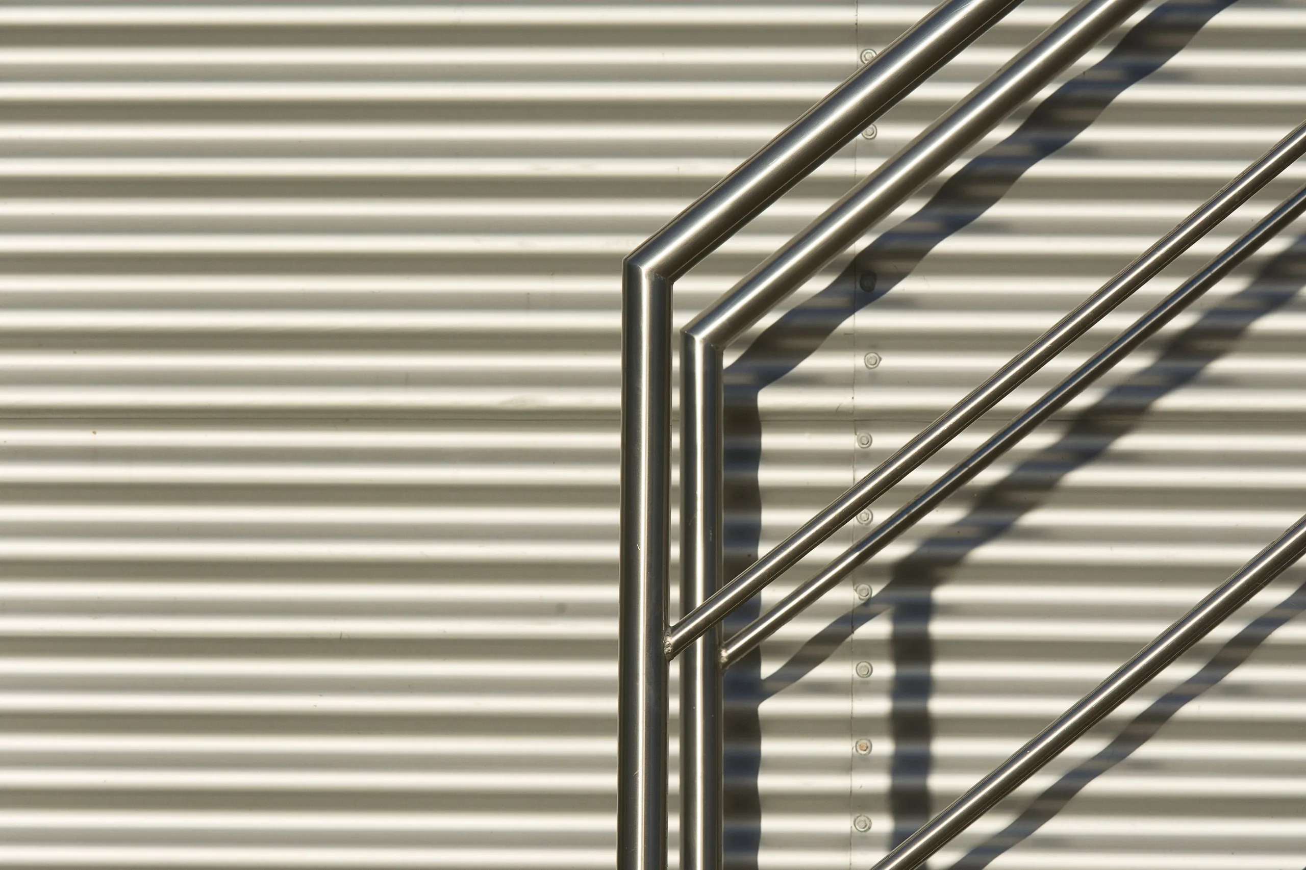 Edelstahlgeländer vor einer Metallfassade, Detailaufnahme